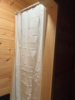 A wooden cabin interior with a white curtain hanging on a wooden door.