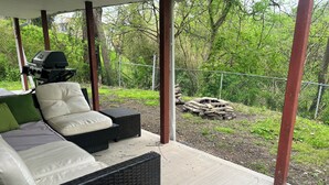 Un espace extérieur aménagé, abrité et doté de meubles en osier et d’un barbecue.