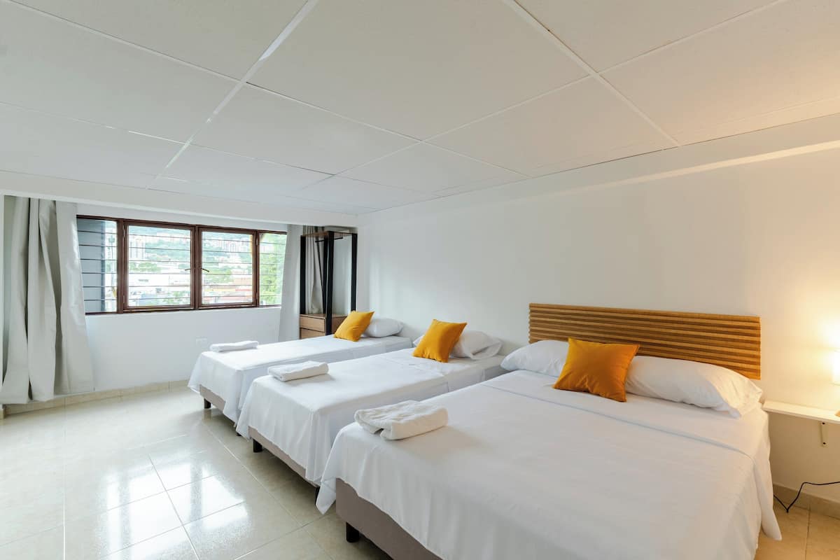 A hotel room with two single beds, a wooden headboard, white bedding, and a window with curtains.