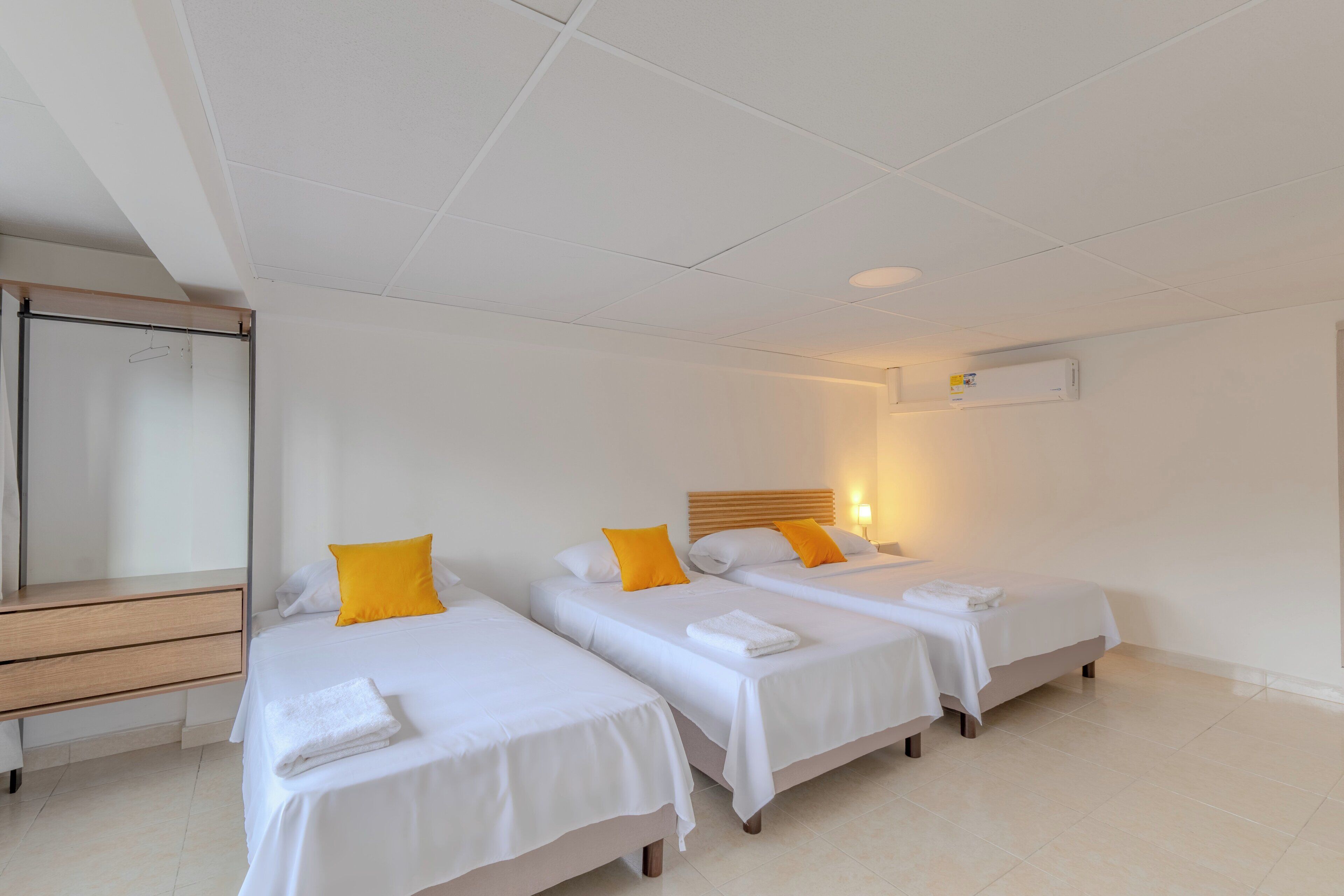 Een hotelkamer met drie enkele bedden, een houten bureau en een spiegel.