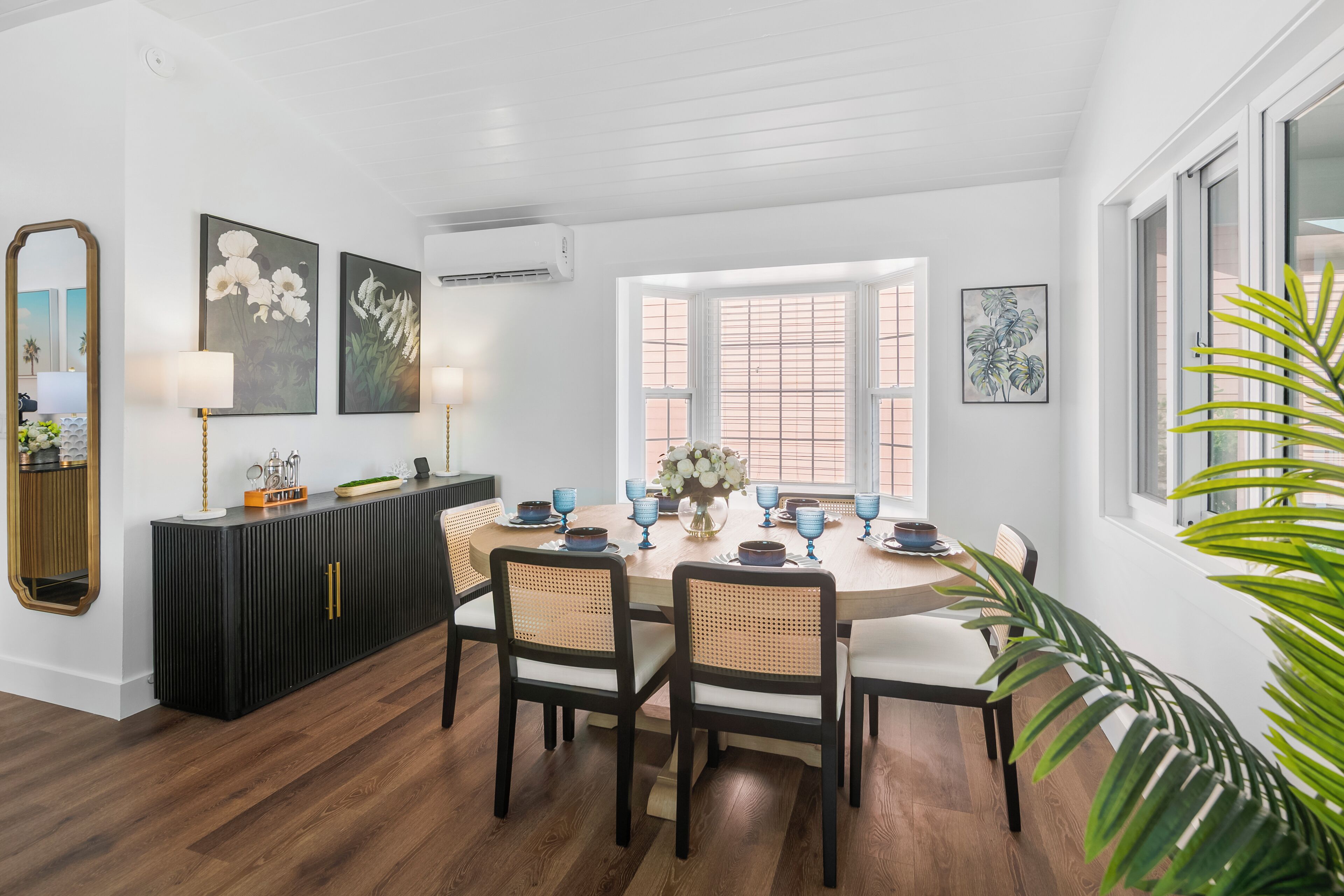 A dining area with a round table, four chairs, a black console, and artwork on the walls.
