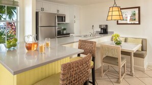 Una cucina moderna con isola centrale, elettrodomestici in acciaio inossidabile e zona pranzo con sedie in vimini e un tavolo.