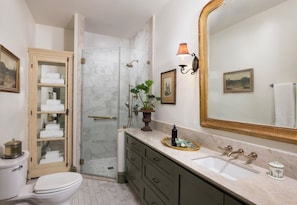 A bathroom with a toilet, a glass-enclosed shower, a vanity with a sink, and a large mirror. - The Marlene Inn (Houston)