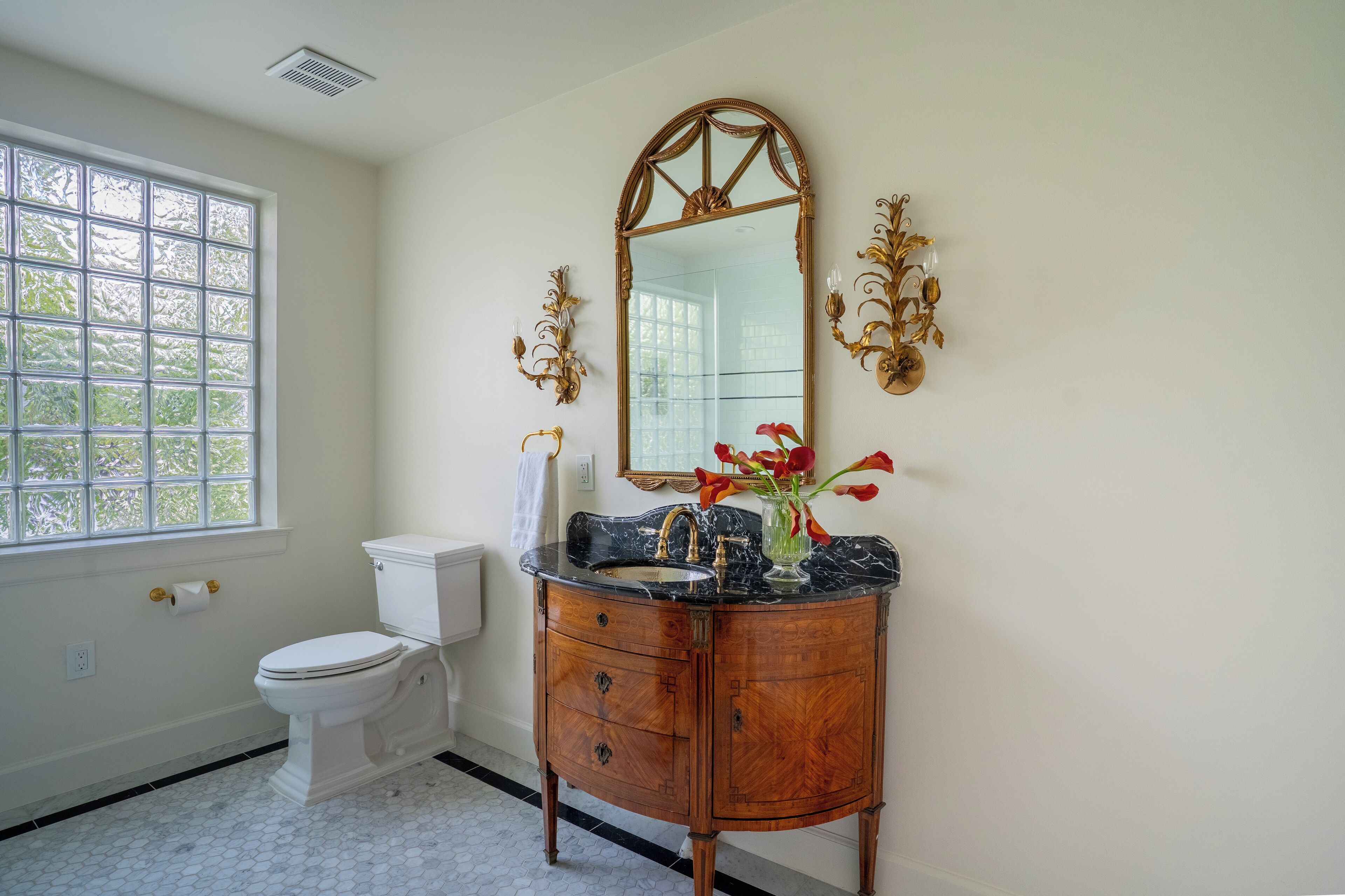 A bathroom with a toilet, vanity, sink, and mirror.