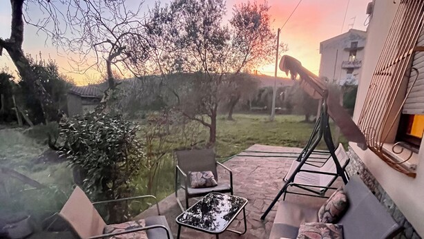An outdoor patio with stone flooring, a fire pit, and two lounge chairs with cushions. - Casa Rina Family home apartment. Umbria / Tuscany. 2 minutes from the lake (Umbria)