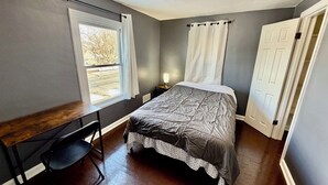 A bedroom with a bed, a desk, a chair, a window, and a door. - single family home, easy access, safe area (South Bend)