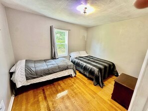 A small room with two beds, a window, and a ceiling fan.