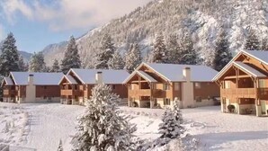 A row of log cabins with snow-covered roofs, set against a backdrop of a snow-covered mountain. - Enjoy our beautiful two-bedroom condo over Christmas break. (Leavenworth)
