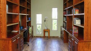 A spacious room with wooden bookshelves, a desk, and a chair. There are two windows providing natural light. - Casa Naranja - Casa de 5 Cuartos 6 baños de Lujo y Confort (Ciudad Fernández)