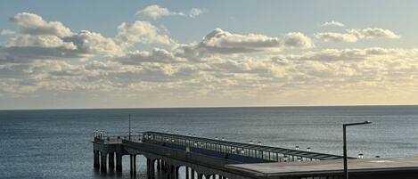 Eine Pier, die sich in ruhiges Wasser erstreckt, mit blauem Himmel darüber.