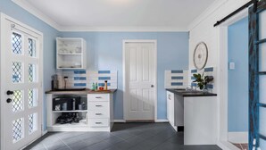 Une cuisine avec des meubles blancs, une porte et un mur bleu.