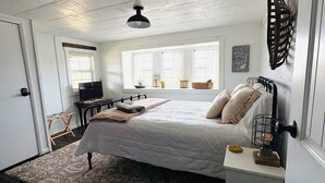 A bedroom with a bed, bedside table, and a window with curtains.