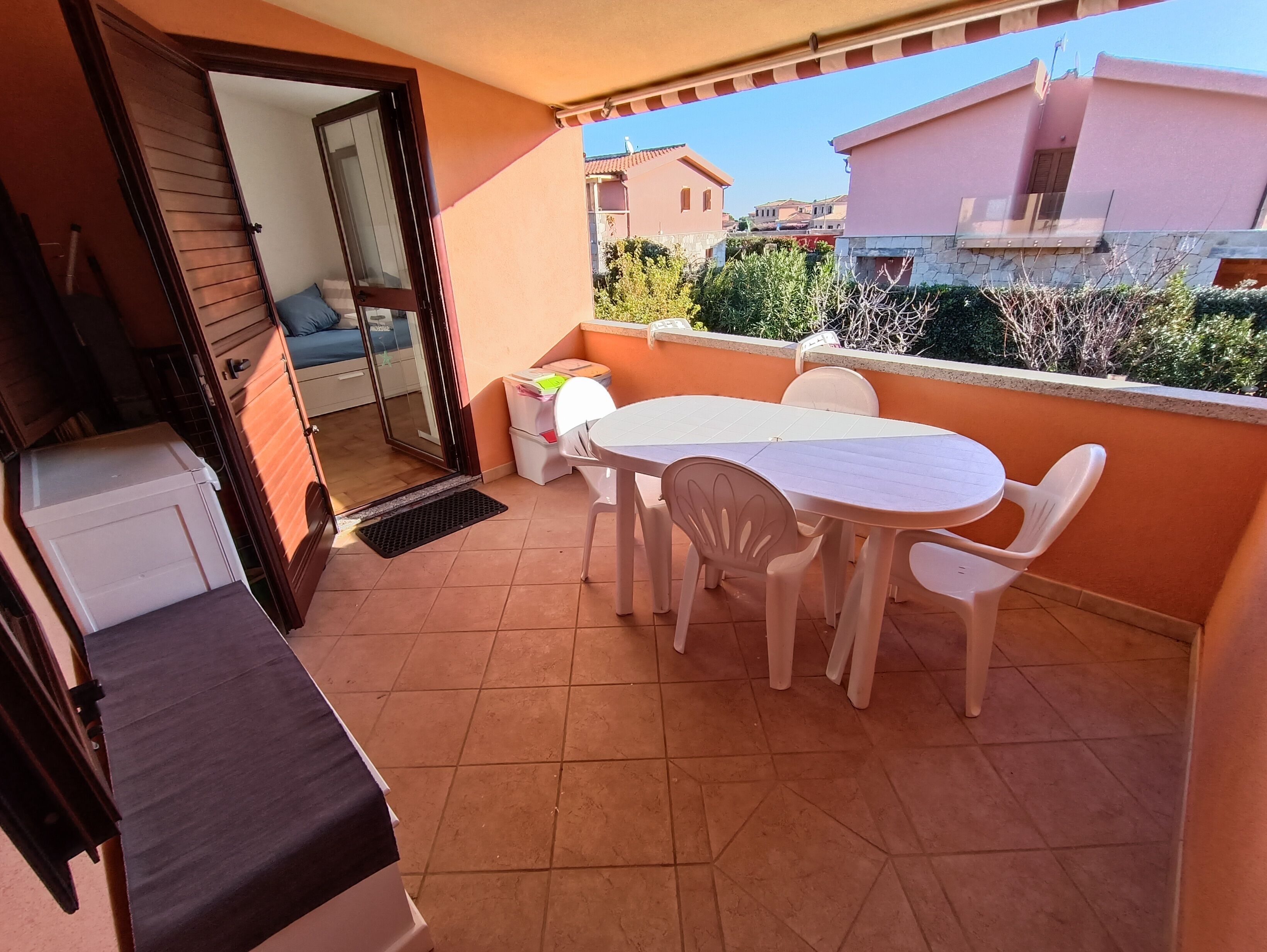 Een balkon met een tafel en stoelen, een barbecue en uitzicht op omliggende gebouwen.