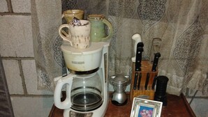 A coffee maker on a wooden table with a picture frame and kitchen utensils. - Phenomenal 1-bedroom campground next to the river in pleasant Santa Cruz. (Santa Cruz)