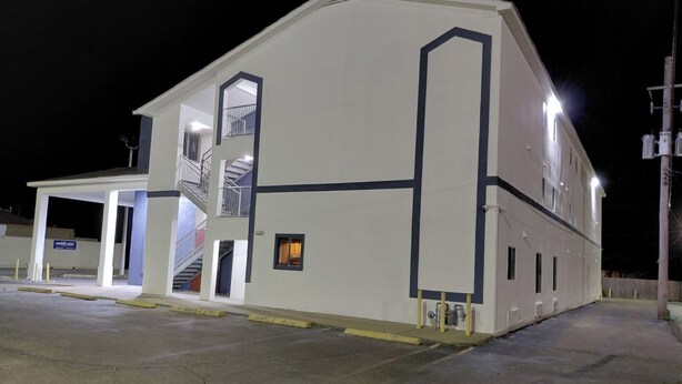 A multi-story building with a covered entrance and a staircase leading to an upper level.