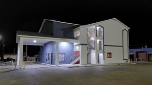 A multi-story building with a covered entrance and a staircase leading to an upper level.