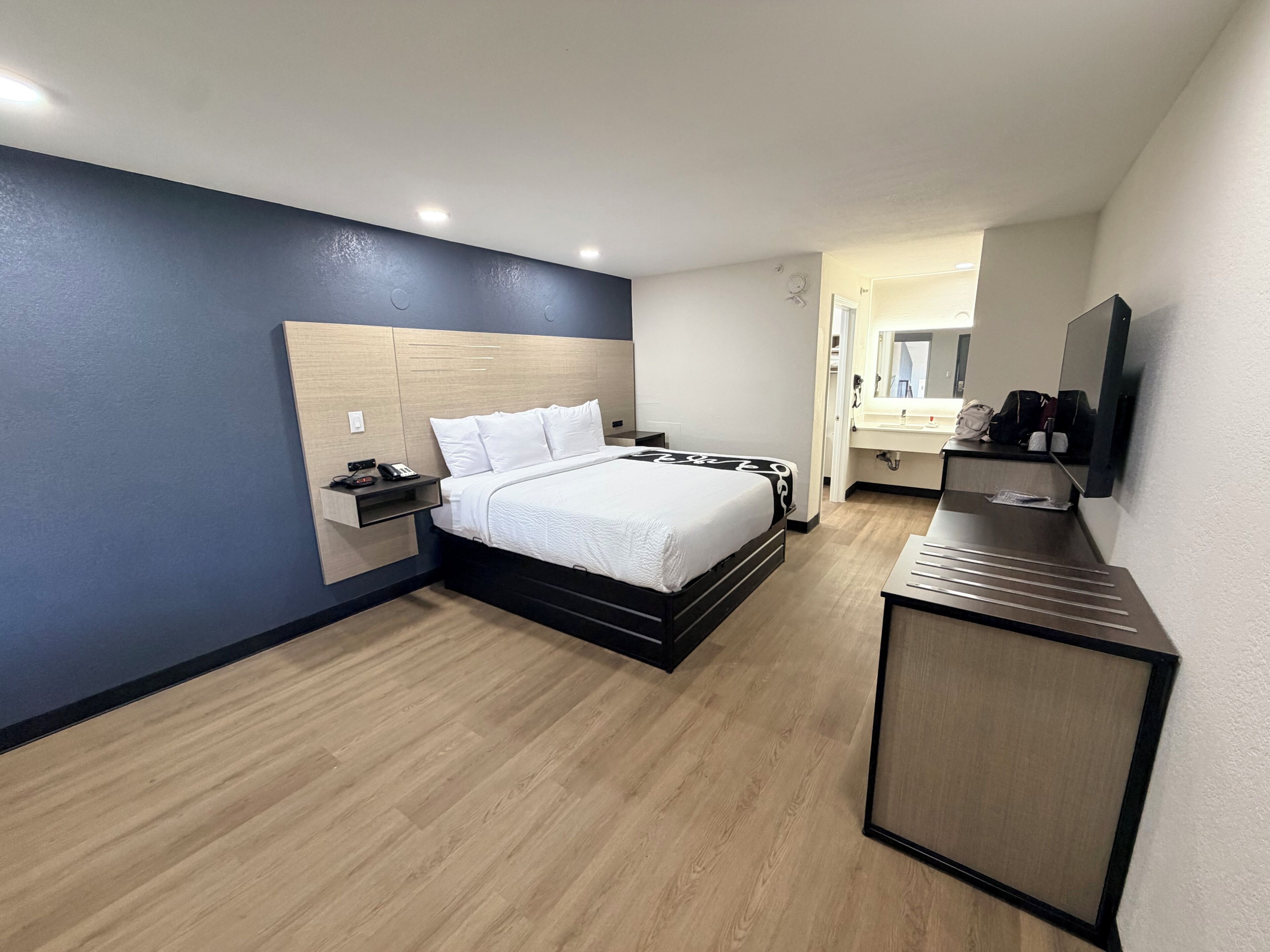 Una habitación de hotel con cama, mesita de noche y escritorio con silla.