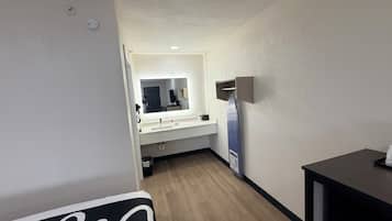A hotel room with a wooden floor, a white sink, a mirror, and a black table.