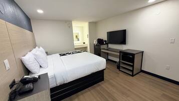 Habitación de hotel con cama, escritorio y televisión.