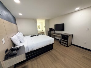 A hotel room with a bed, desk, and TV.