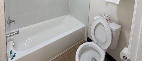 Un baño con bañera, inodoro y estante con toallas.