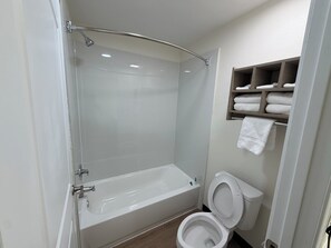 A bathroom with a bathtub, toilet, and a shower enclosure. - Springplace Inn & Suites (Millington)