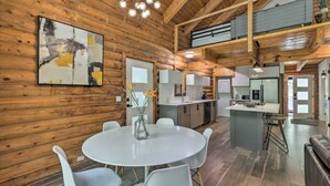 Intérieur moderne d’une cabane en rondins, comprenant un coin repas, une cuisine et un espace de vie.