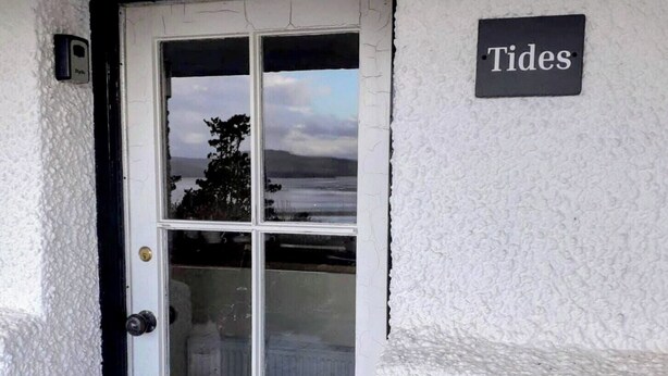 En hvid dør med et glaspanel, en sort dørkarm og et skilt med teksten "Tides" på væggen.