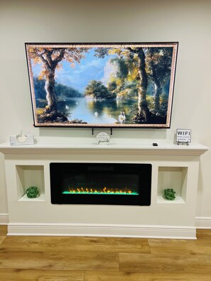 Un téléviseur à écran plat fixé sur un meuble de télévision blanc, avec une cheminée en dessous.