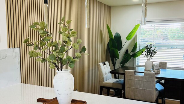 Une cuisine moderne avec un plan de travail blanc, un mur recouvert de panneaux en bois et des luminaires suspendus.
