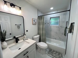 A modern bathroom with a white sink, mirror, toilet, and bathtub. - Modern Oasis Near Hard Rock Tampa (Tampa)