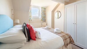 A hotel room with a large bed, a window with curtains, a bedside table with a lamp, a chair, and a wardrobe. - 2 bedroom self catering apartment with amazing views Chalet studio (Grange-over-Sands)
