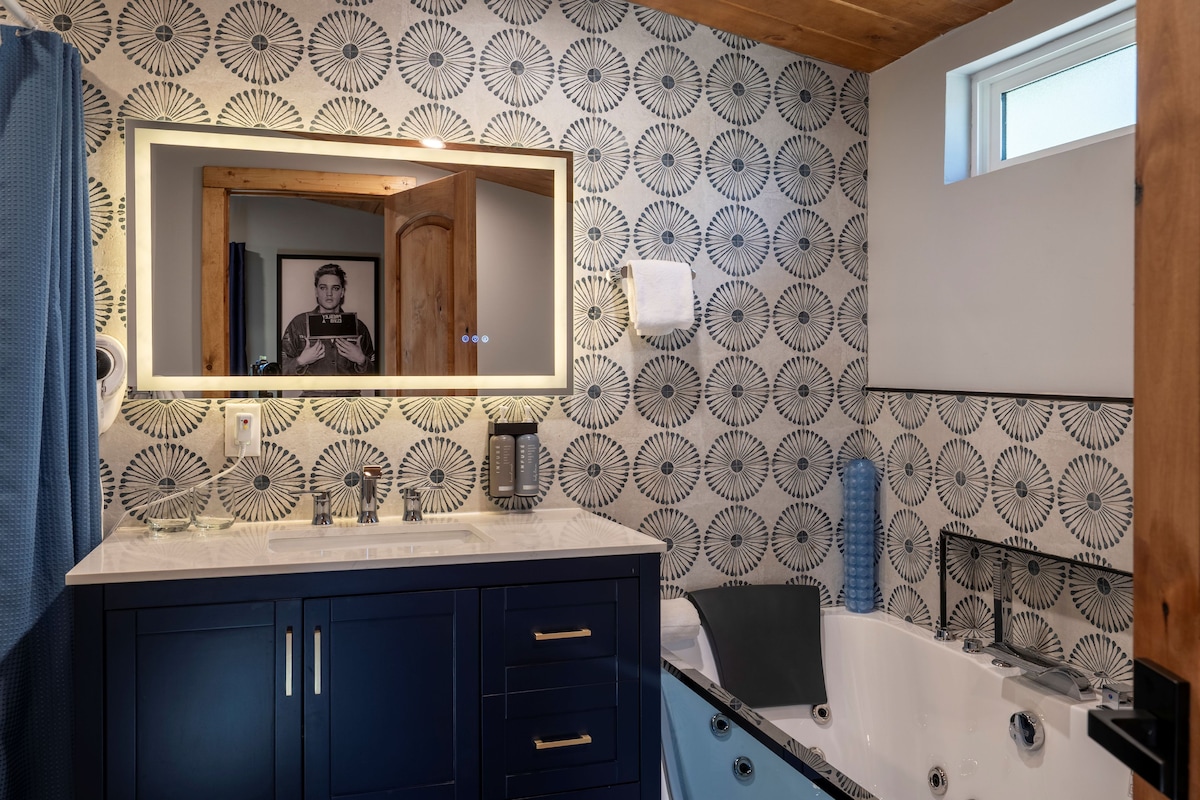 A bathroom with a vanity, a bathtub, and a mirror with a wooden frame.