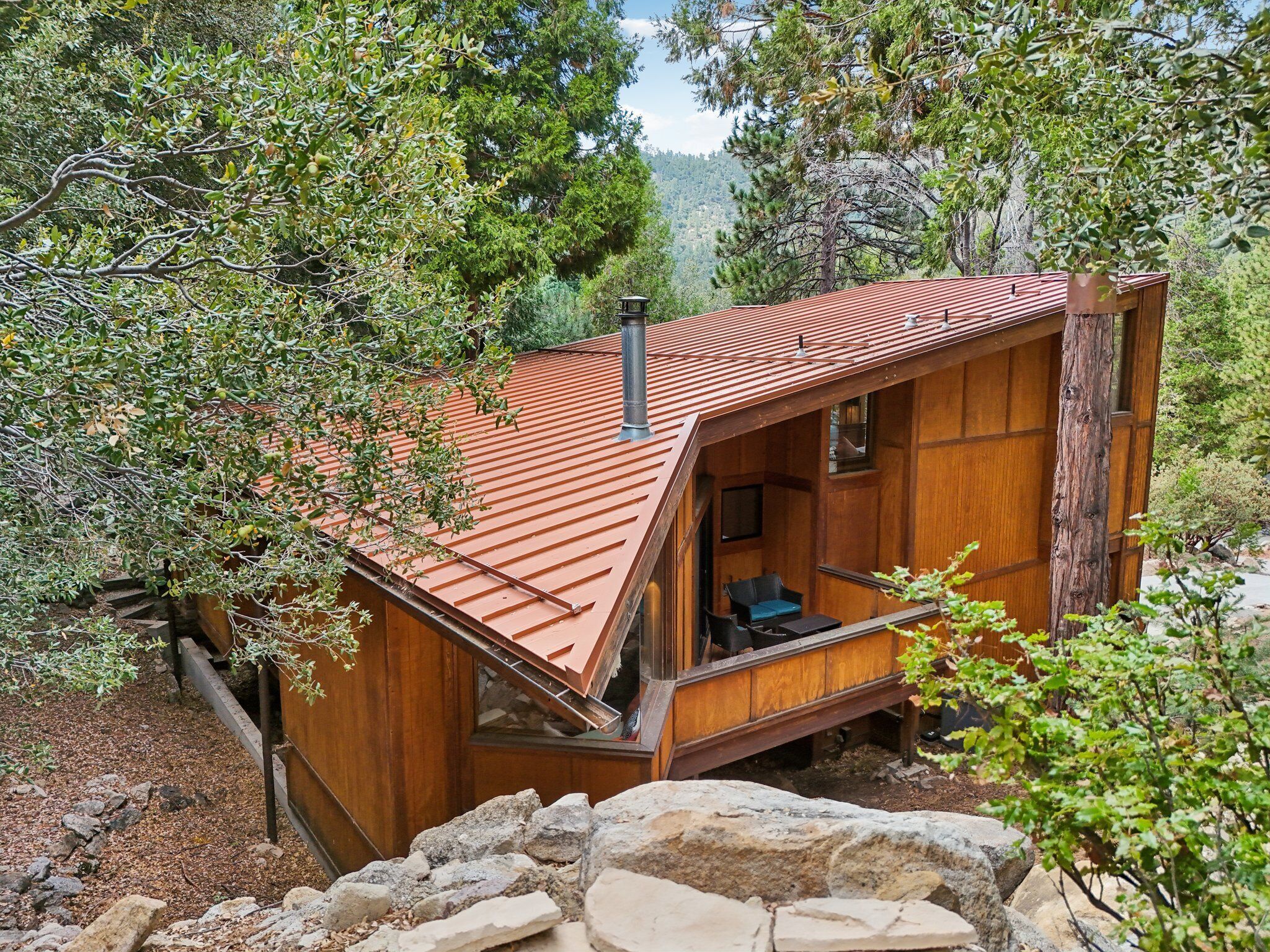 Eine rustikale Holzhütte mit geneigtem Dach, Holzfassade und einer kleinen Veranda.