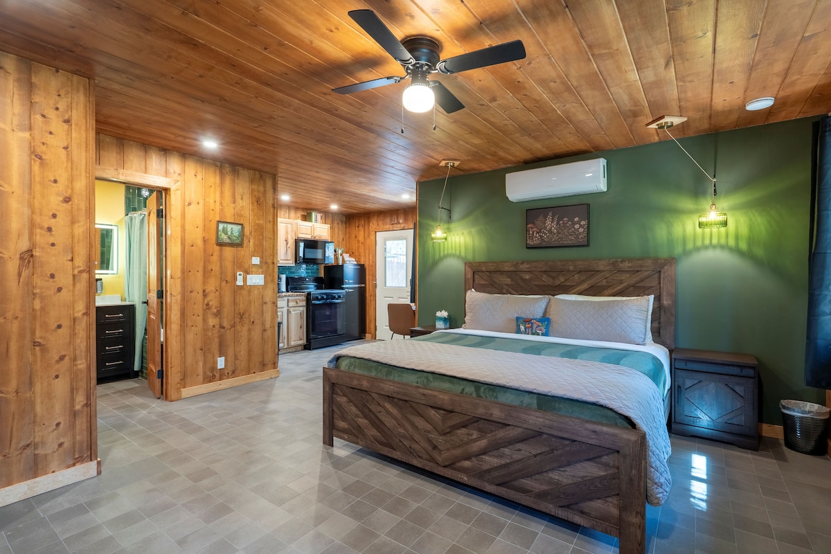 A bedroom with a wooden bed frame, a ceiling fan, and a green wall.