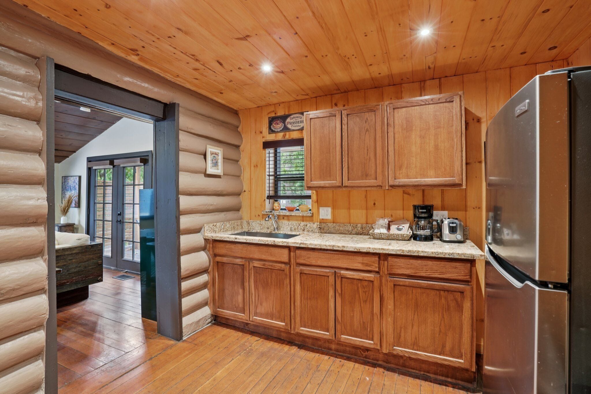 Una cocina de estilo cabaña con armarios de madera, un refrigerador de acero inoxidable y una encimera de granito.