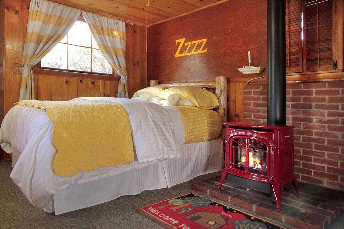 A cozy room with a bed, a fireplace, and a window with curtains.