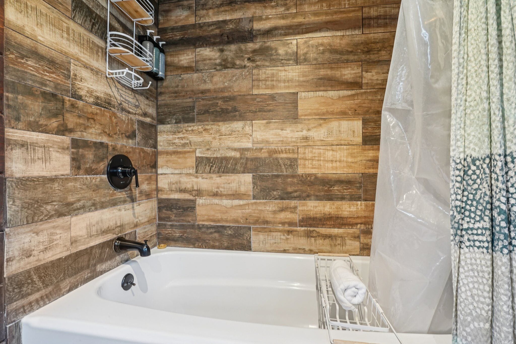 A bathroom with a wooden wall, a bathtub, a towel rack, and a shower curtain.