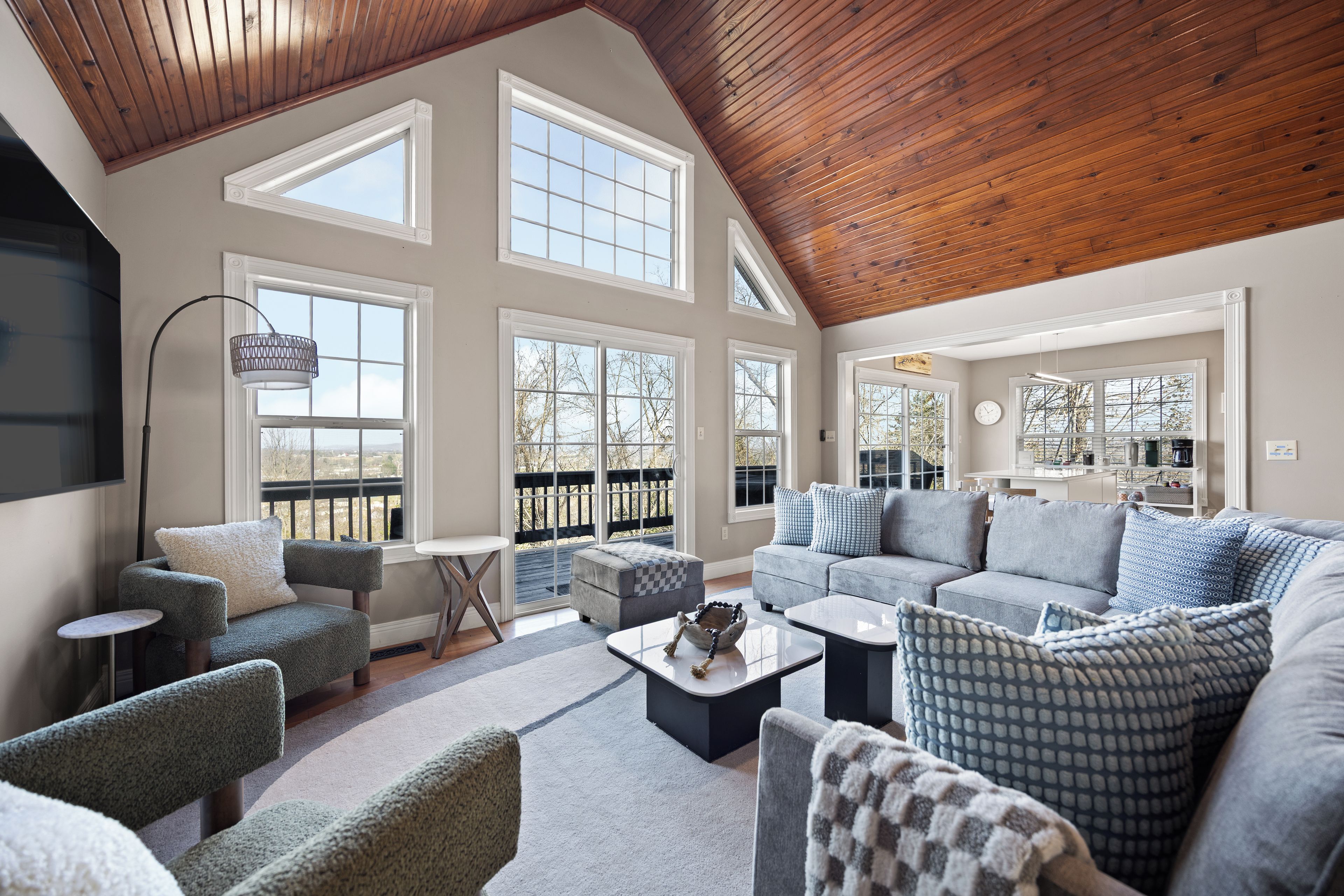 A spacious living room with a high ceiling, large windows, and a cozy seating area.