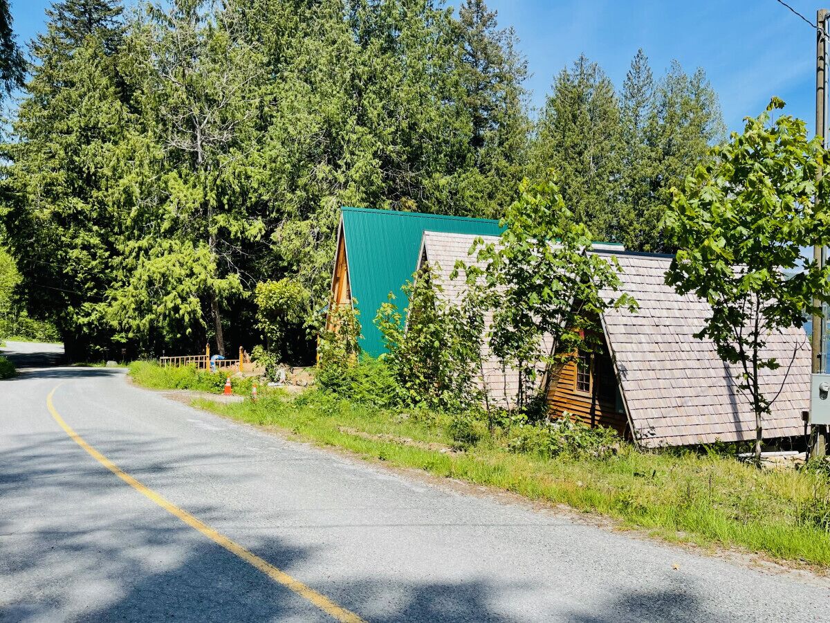 Una strada di campagna con una casetta di legno e un edificio con il tetto verde.