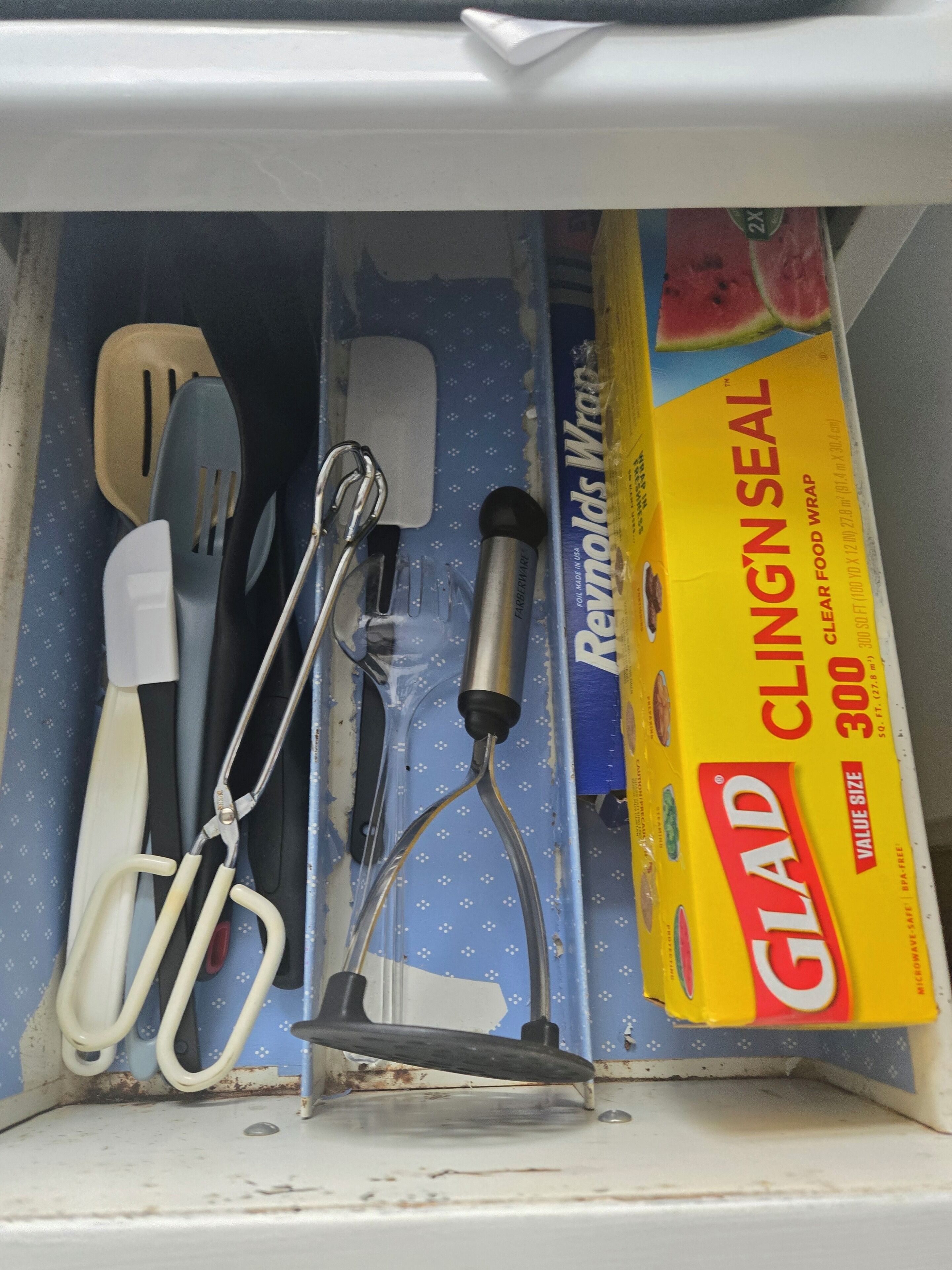 Eine Schublade mit Küchenutensilien, darunter ein Pfannenwender, Zangen und ein Schneebesen.