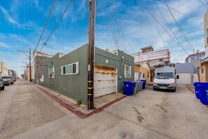 A street view with buildings, a parked truck, and blue bins. - Homey Cottage w/ Ocean View Patio (San Diego)