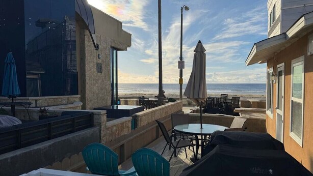 Eine Terrasse im Freien mit Sitzgelegenheiten, einem Tisch und Blick aufs Meer.
