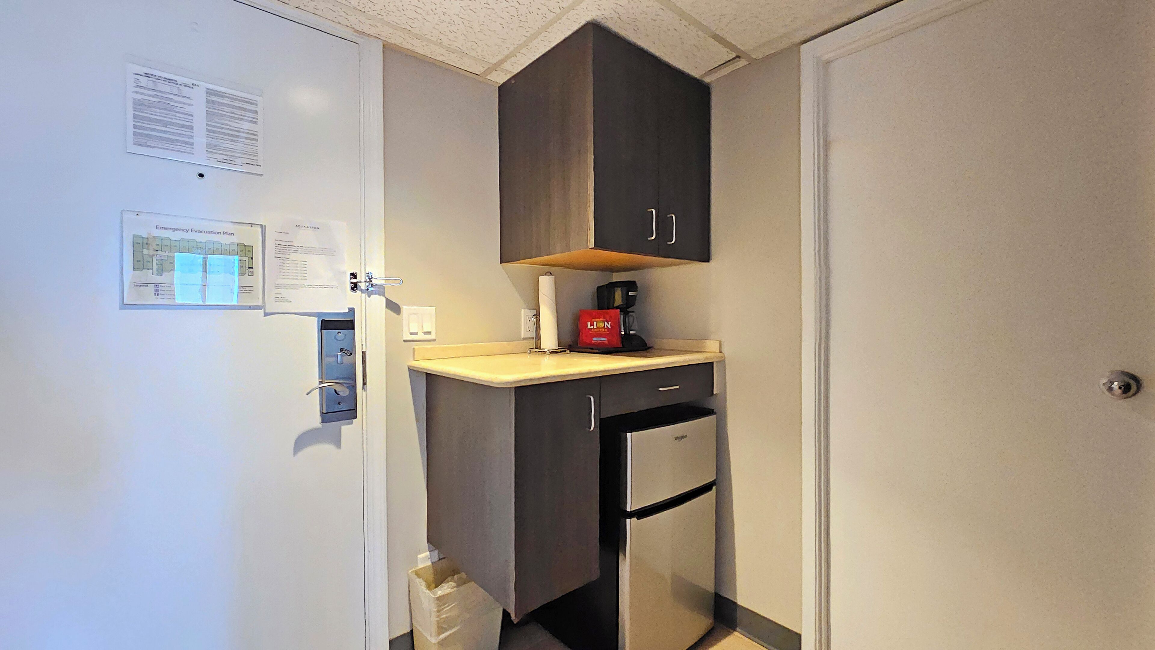 Una cocina compacta con refrigerador, cafetera y una pequeña encimera.