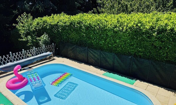 A swimming pool with a pink flamingo float and a rainbow float.