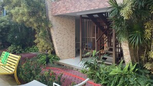 Un edificio de dos plantas con fachada de ladrillo, un balcón con barandilla de vidrio y una escalera que conduce al nivel superior.