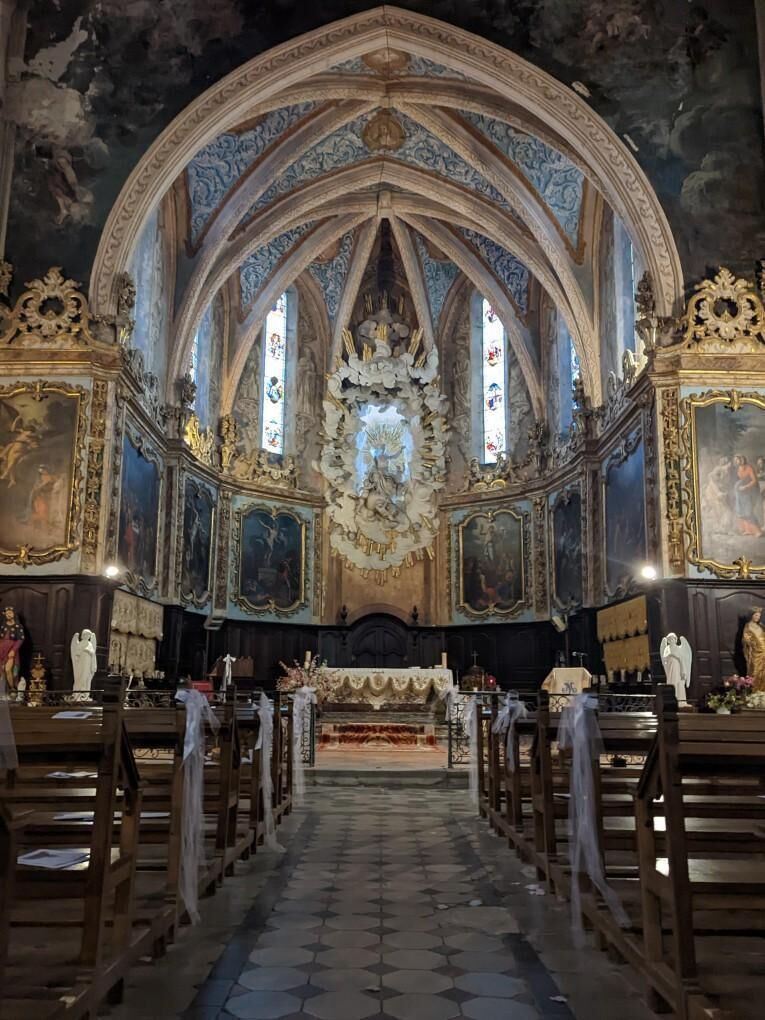 An ornate church interior with a central altar, pews, and religious statues.