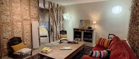 A living room with a wooden coffee table, a red sofa, a stone wall, and a hanging chair.