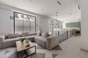 A modern living room with a sectional sofa, a wooden coffee table, and a large window. - Waou Urban Home Chamberi X (Madrid)