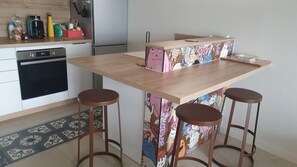 A kitchen with a wooden island, two stools, a dishwasher, and a refrigerator. - La Plagette - LEUCATE (LEUCATE)